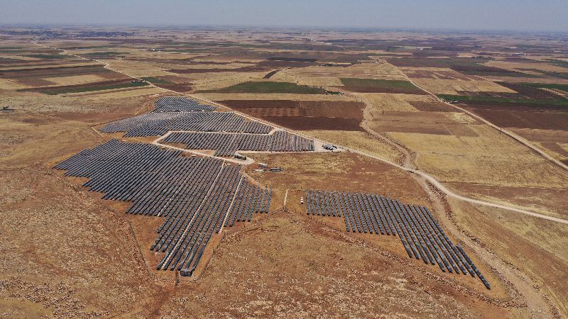 Santralin yüksekten kuş bakışı görünümü: panel blokları ve çevresini saran parsellenmiş tarım arazileri